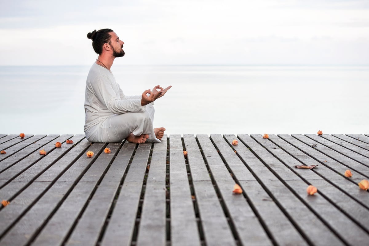 Man Meditating on Wooden Pier